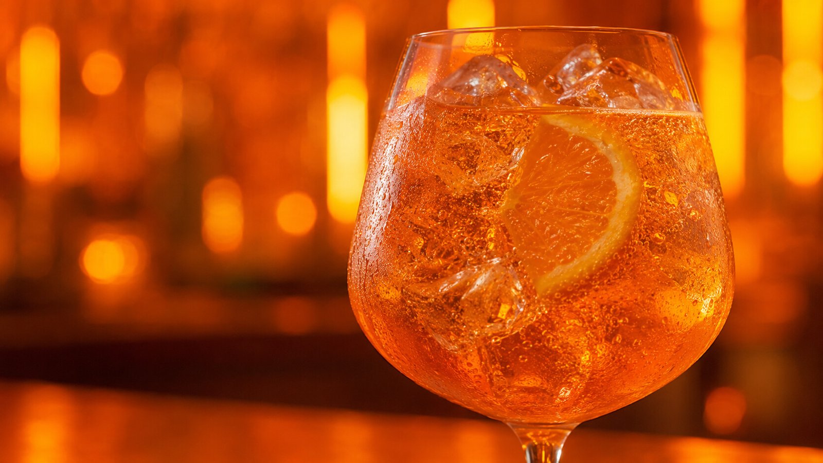 Alkoholfreier Aperol Spritz vor passendem orangefarbenem Neonlicht