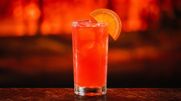 Campari Orange vor extrem unscharfem Neonhintergrund in der Farbe des Drinks