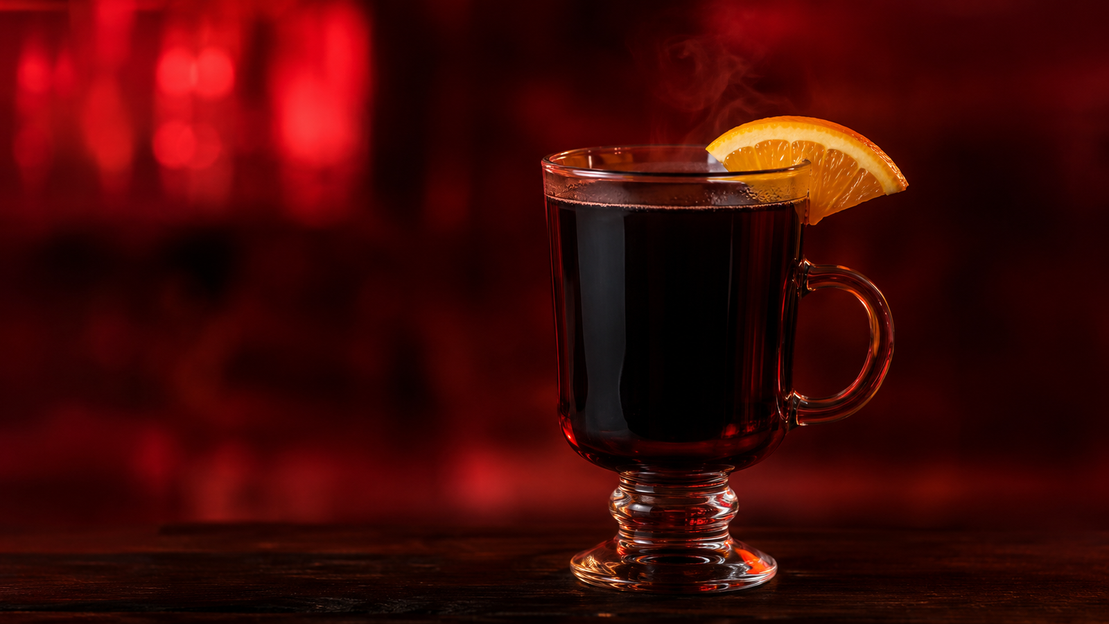 Glühwein vor extrem unscharfem Neonhintergrund in der Farbe des Drinks
