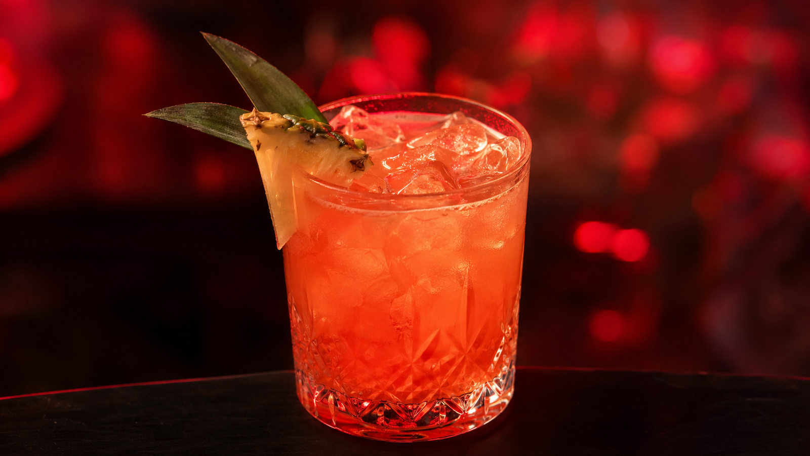 Jungle Bird vor extrem unscharfem Neonhintergrund in der Farbe des Drinks