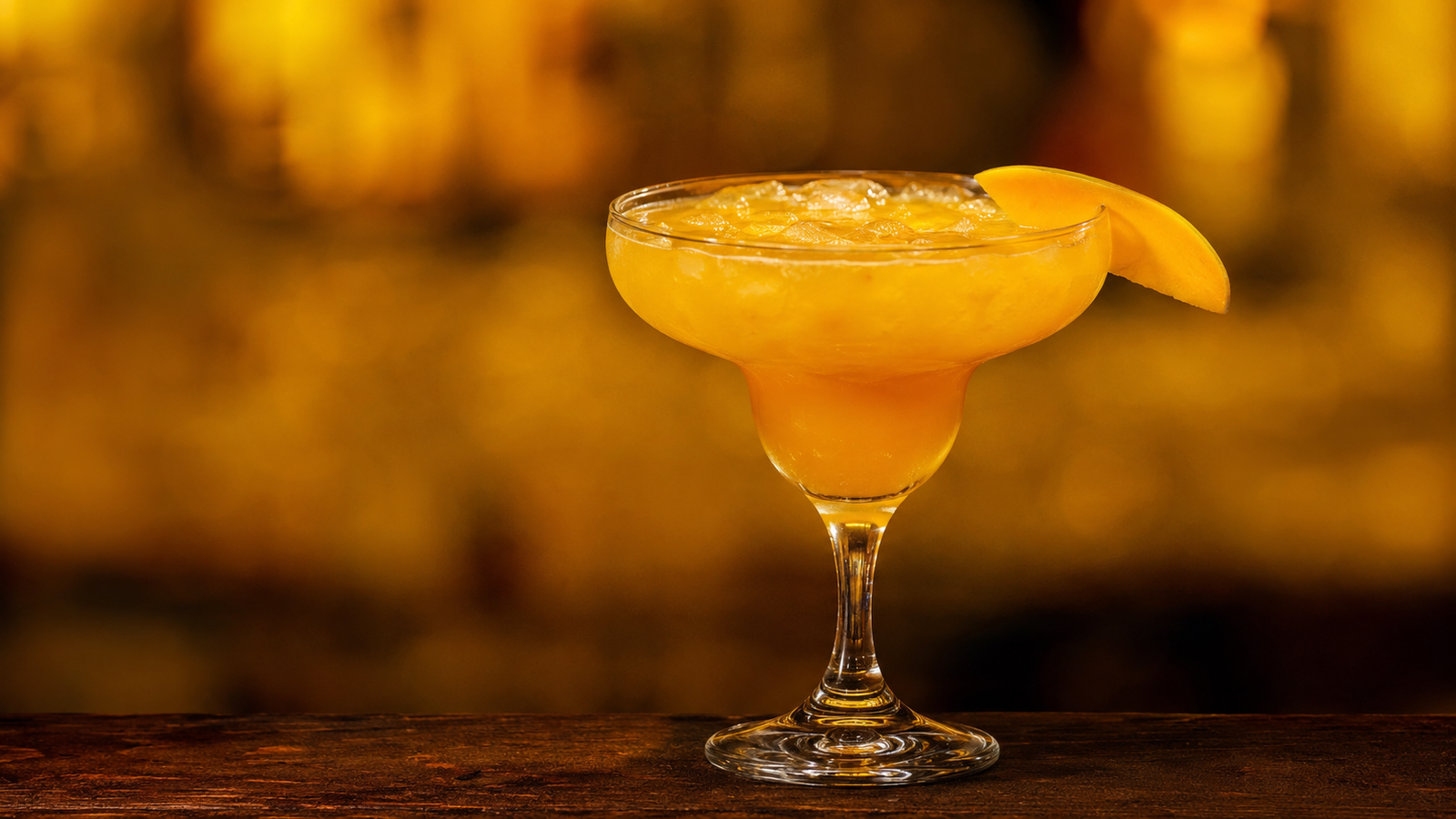 Mango Margarita vor extrem unscharfem Neonhintergrund in der Farbe des Drinks
